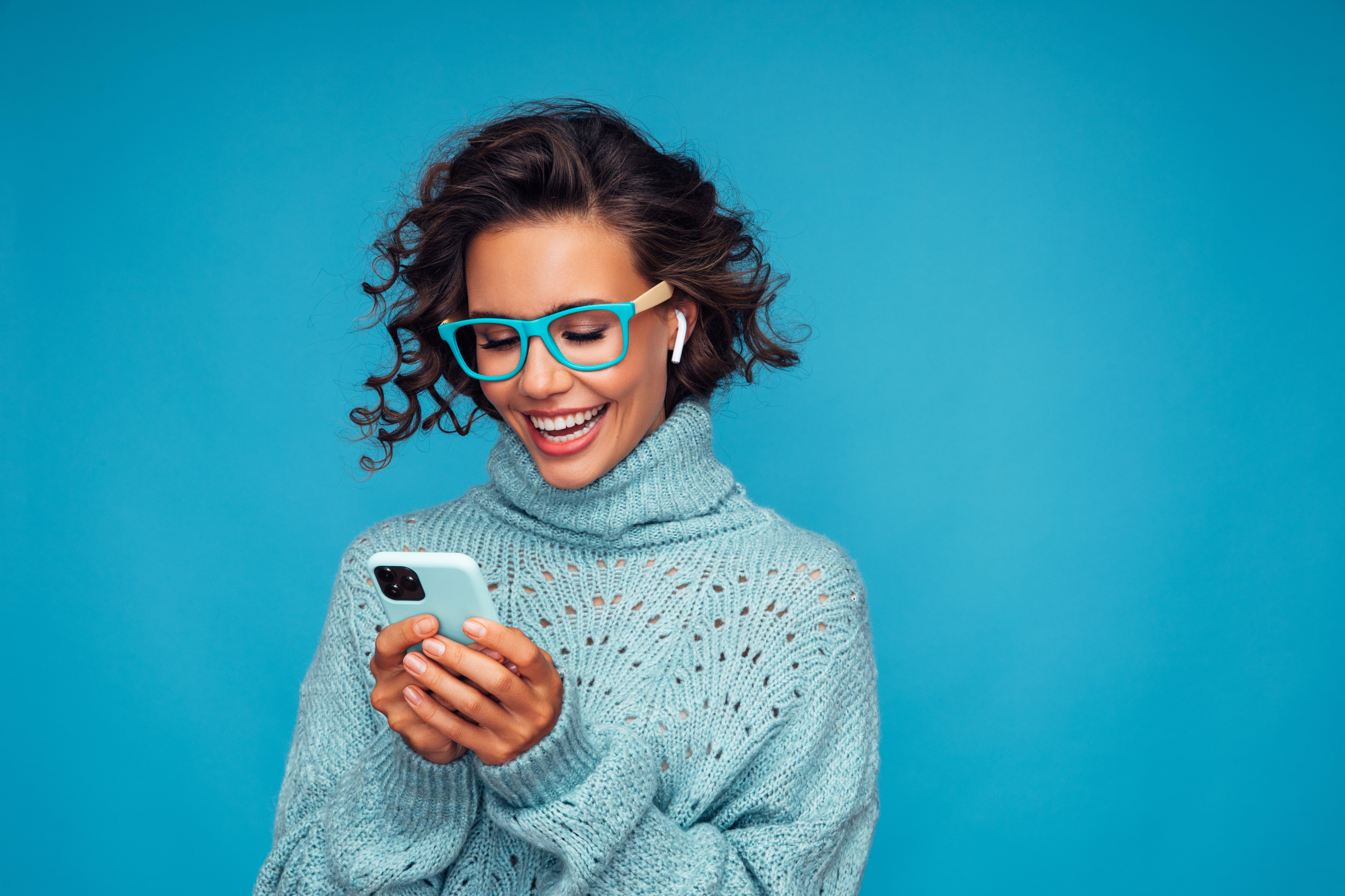 모바일 기기를 보고 있는 파란색 안경을 쓴 여성.jpg